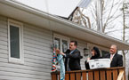 Suburban Priorities Team members Mat Whynott and Sid Priest and Service Nova Scotia and Municipal Relations Minister Ramona Jennex hang clothes on a clothesline below a solar panel.